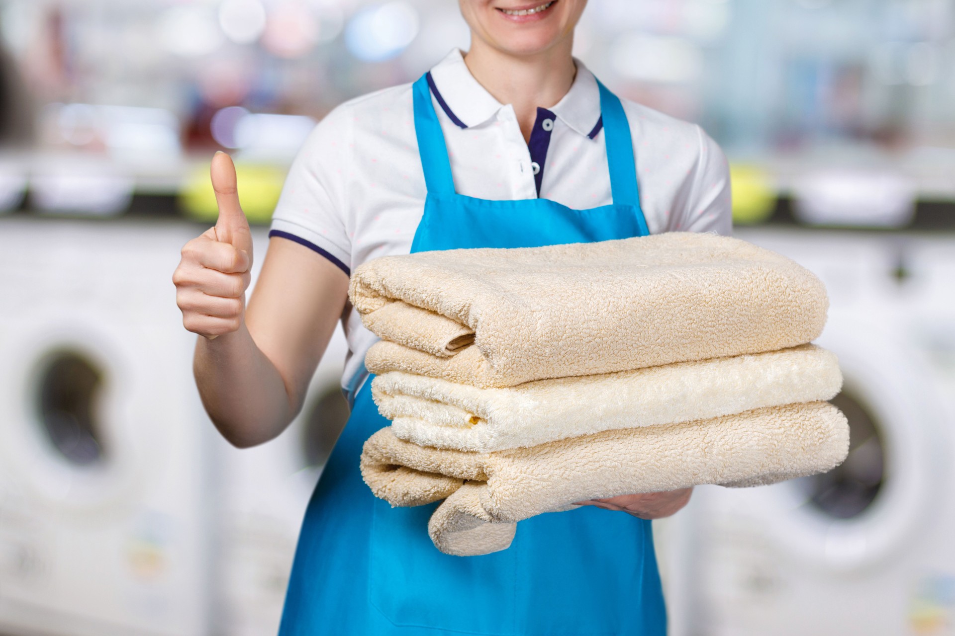 A laundry worker is holding clean towels.
