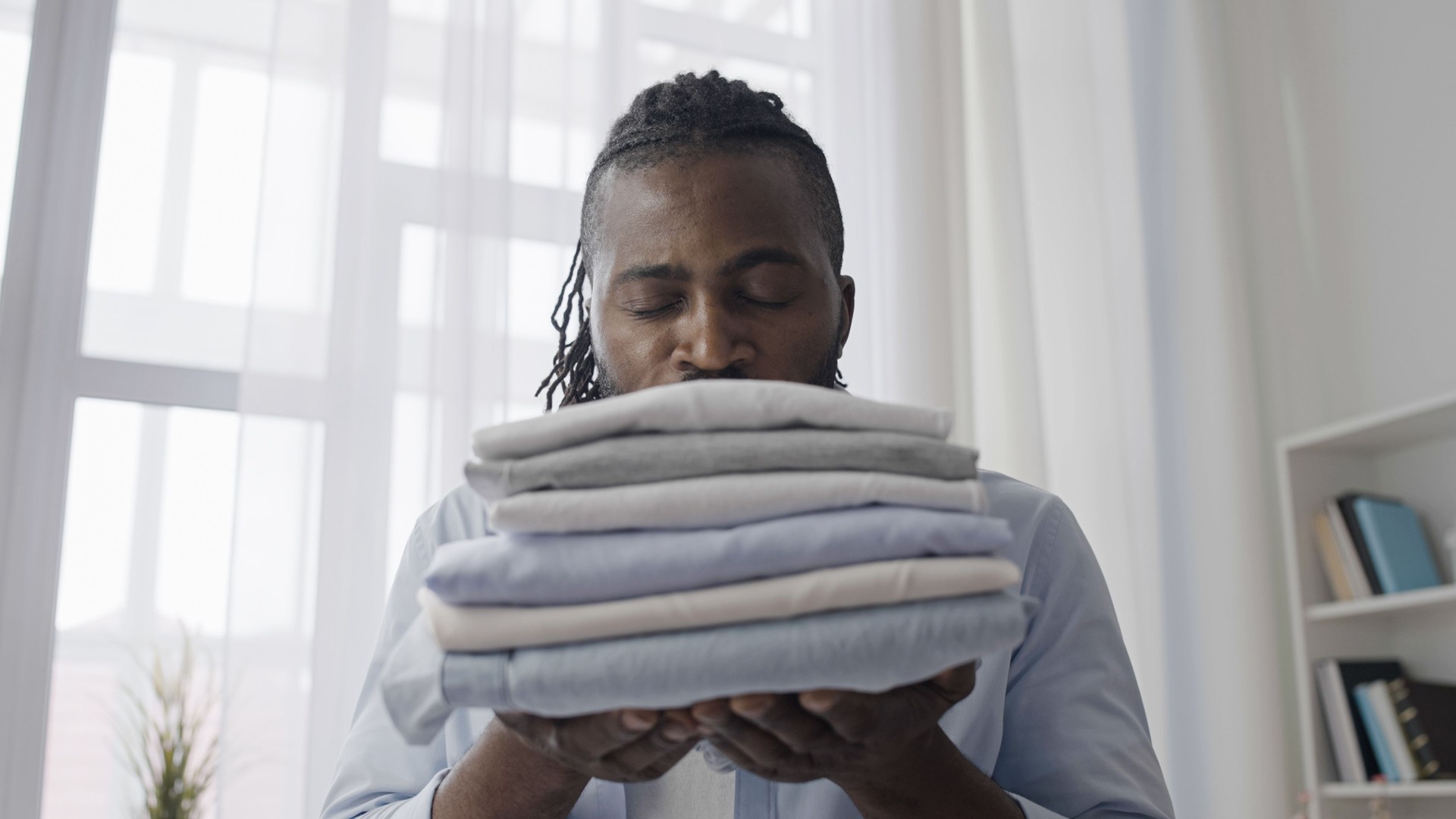 African American man enjoying the smell of freshly washed and ironed clothes, new fabric softener